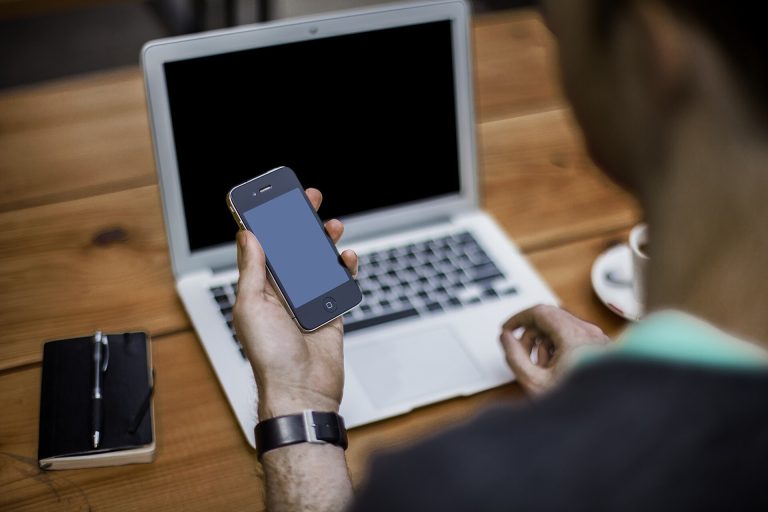 Managing Account Information Man using a smartphone and a laptop at a desk